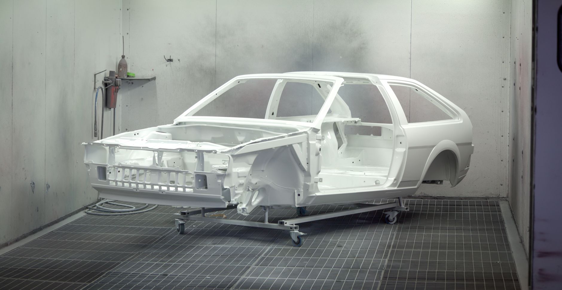 Car frame being painted in an automotive paint booth
