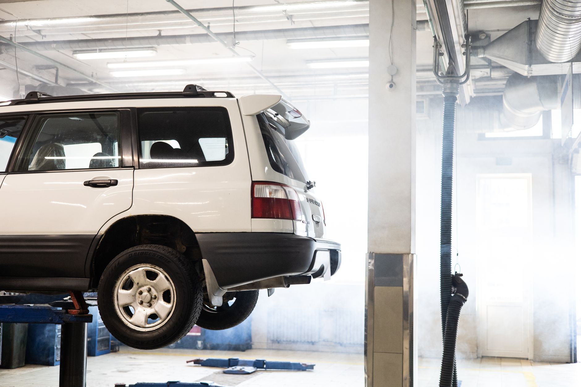 White SUV elevated on a lift inside an auto repair shop