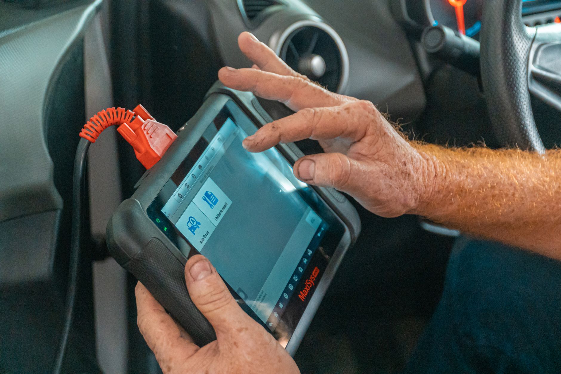 Mechanic using a diagnostic tool inside a car to check for issues