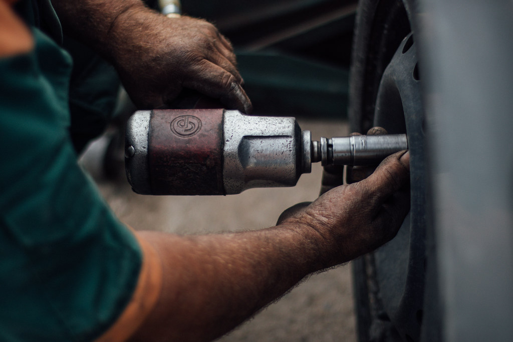 Technician using an impact wrench to remove lug nuts during wheel service