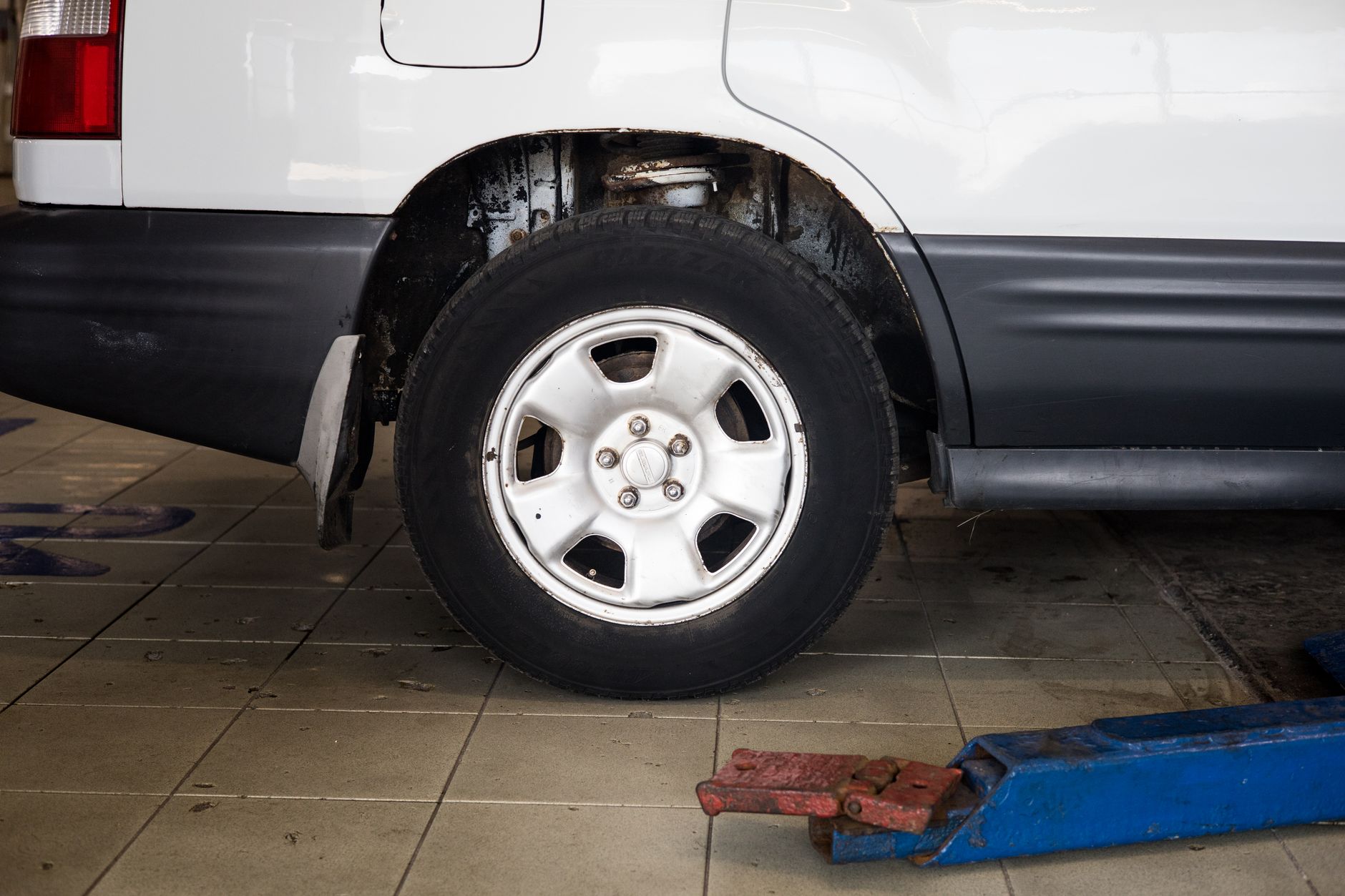 A car wheel on a hydraulic jack during tire service at an auto shop